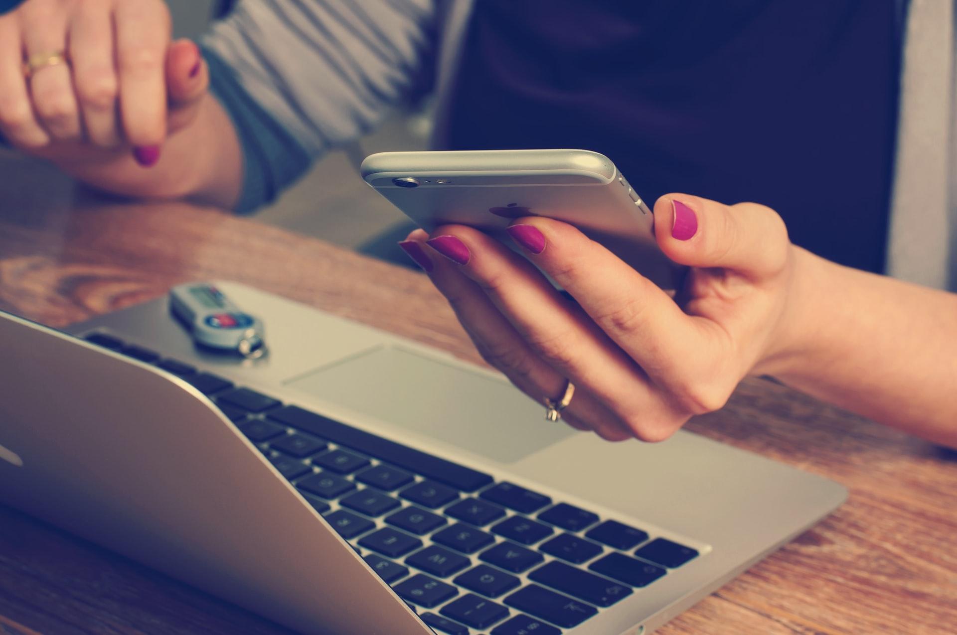 Woman holding phone in front of laptop